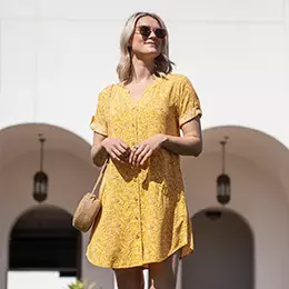 Woman standing outside wearing gold Dell shirt dress.